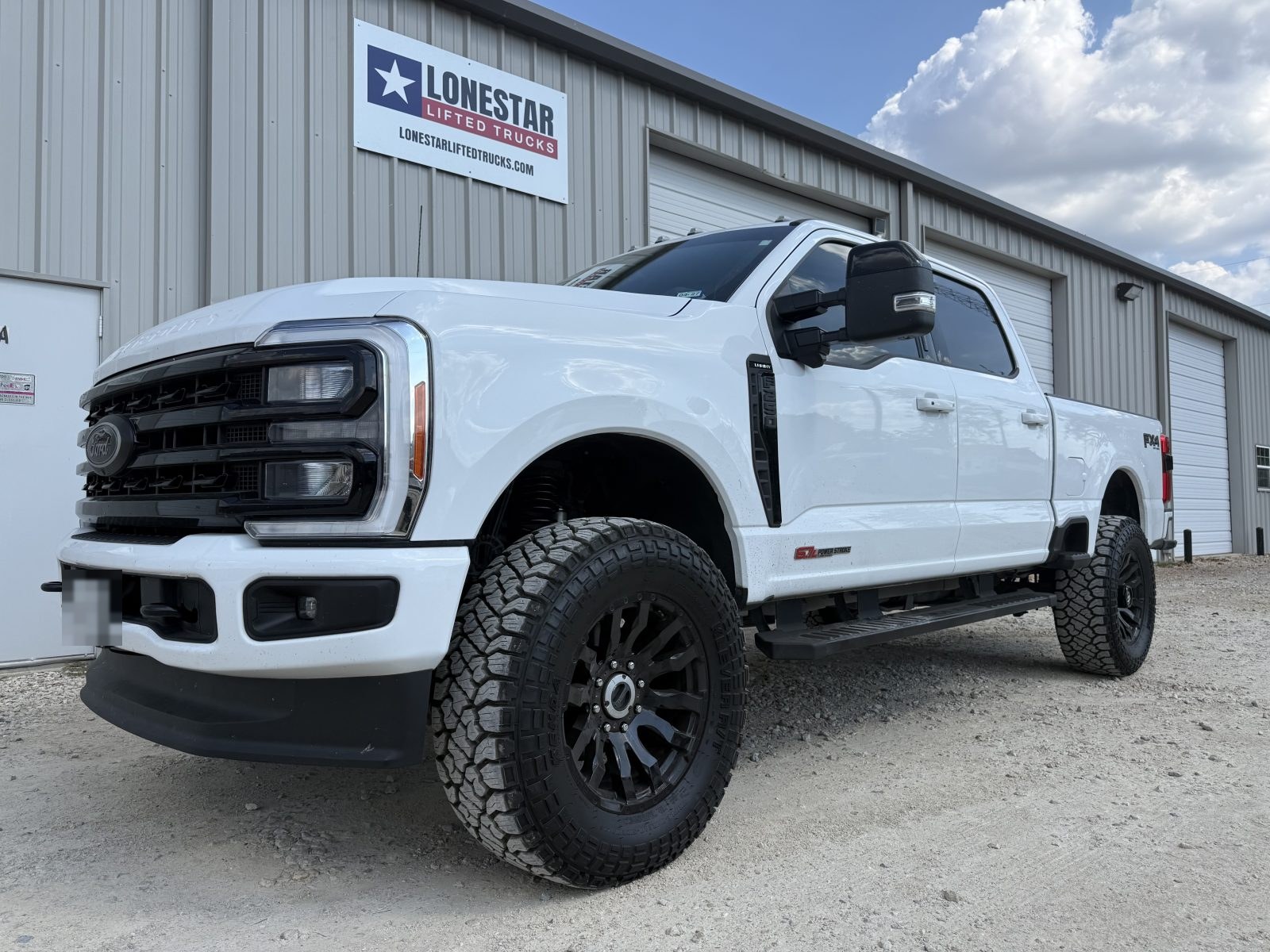 White Ford F-250 Super Duty leveled on 37-inch tires with a Carli track bar and FOX shocks at LONESTAR Lifted Trucks, Argyle TX